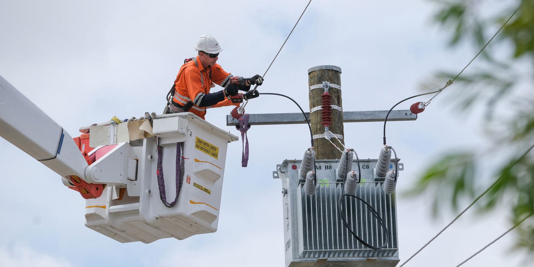 Western Power crew member working on a transformer that attached to a pole