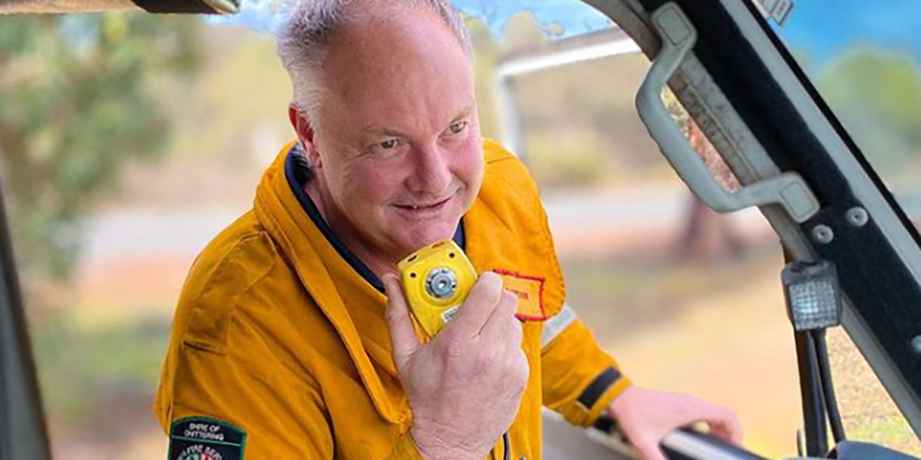 A bushfire volunteer in uniform speaking on his CB radio