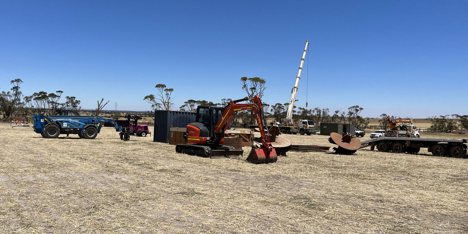 Tractors, cranes and other heavy machinery in a field as the work begins to rebuild a transmission tower