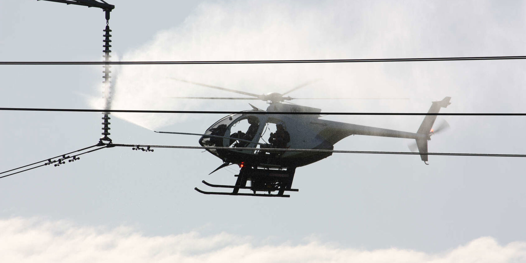 A helicopter carry out line washing on some electricity lines