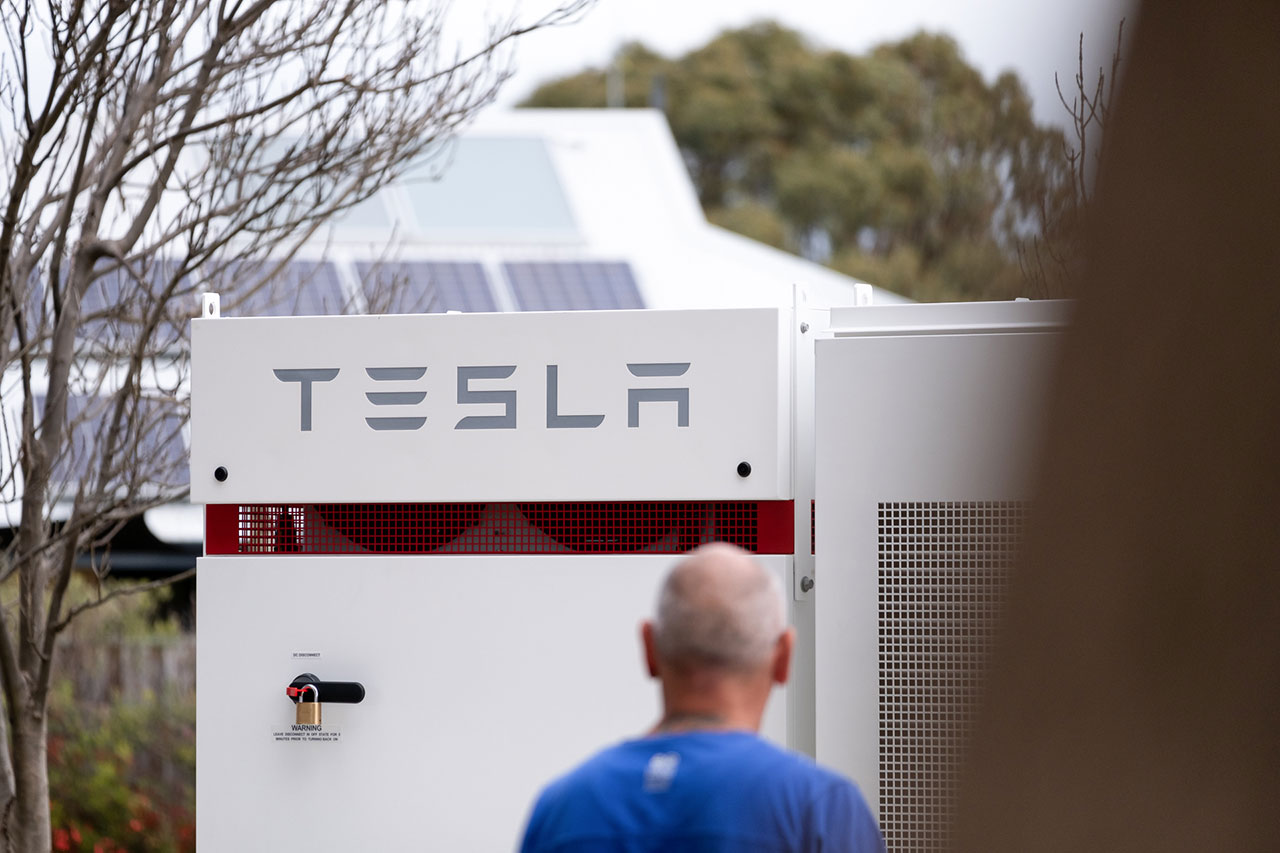 man standing front of tesla battery